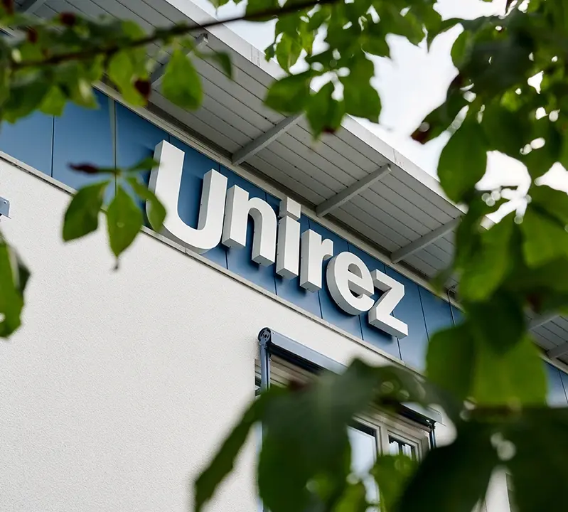 Außenansicht Unirez Geschäftsgebäude, Nahaufnahme Logo an Außenfront vom Gebäude.