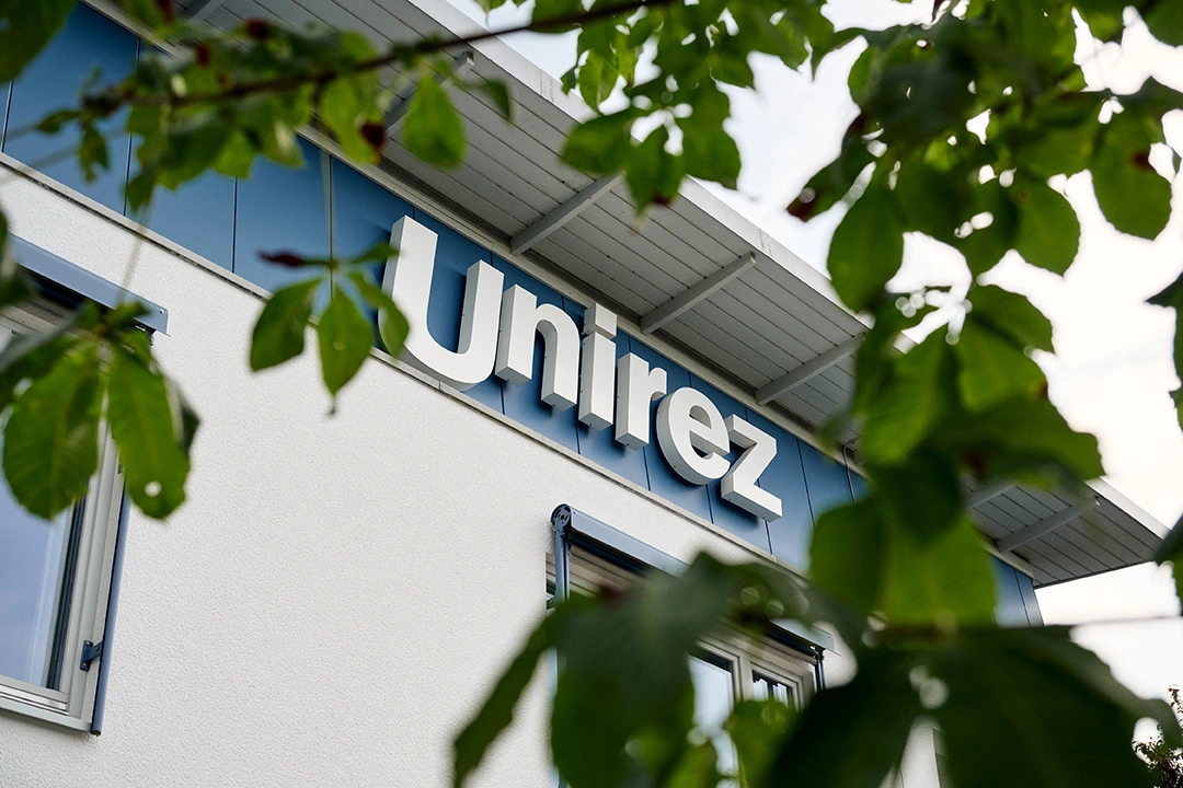 Außenansicht Unirez Geschäftsgebäude, Nahaufnahme Logo an Außenfront vom Gebäude.