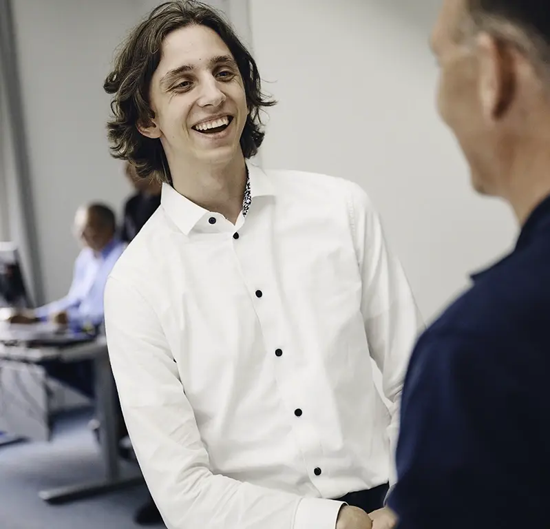 Junger, freundlich lächelnder Mann mit weißem Hemd im Gespräch mit einem Unirez-Mitarbeiter.