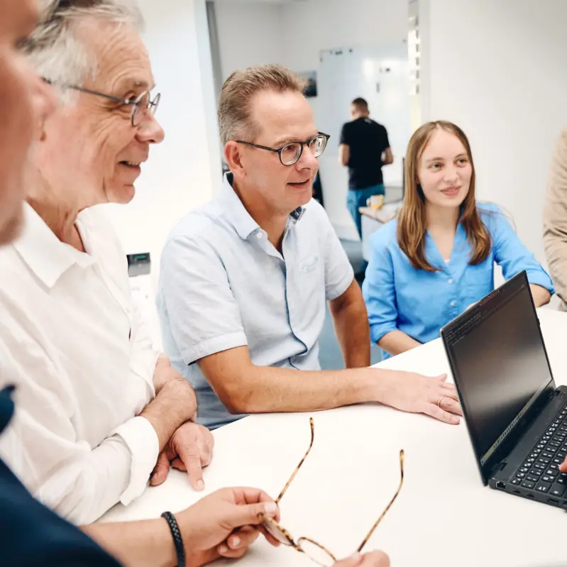 Verschiedene Mitarbeiter und Mitarbeiterinnen von Unirez, die sich an einem Stehtisch unterhalten.